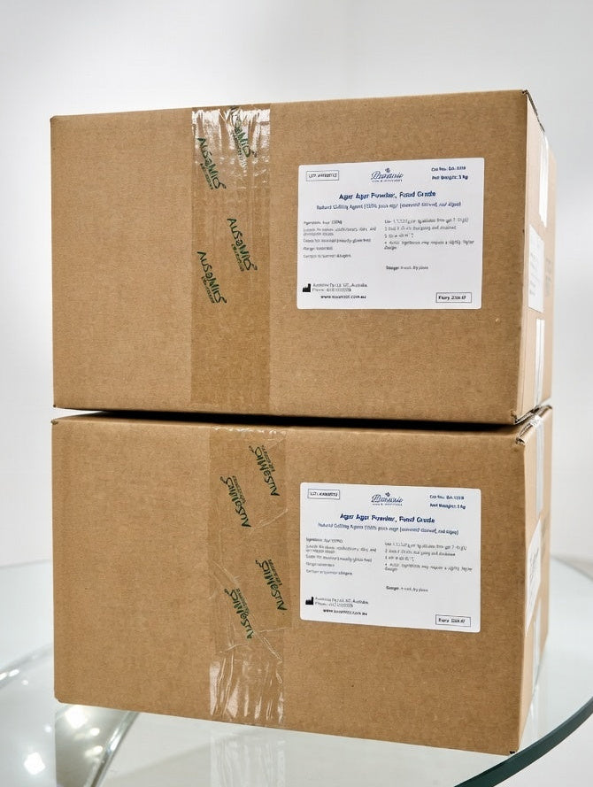 Two stacked agar agar filled cardboard boxes with labels on a reflective surface